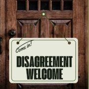 Wood door with sign saying, "Come in, Disagreement Welcome!"
