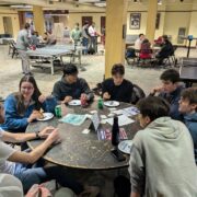 photo of students deliberating around a table with ping pong in the background.
