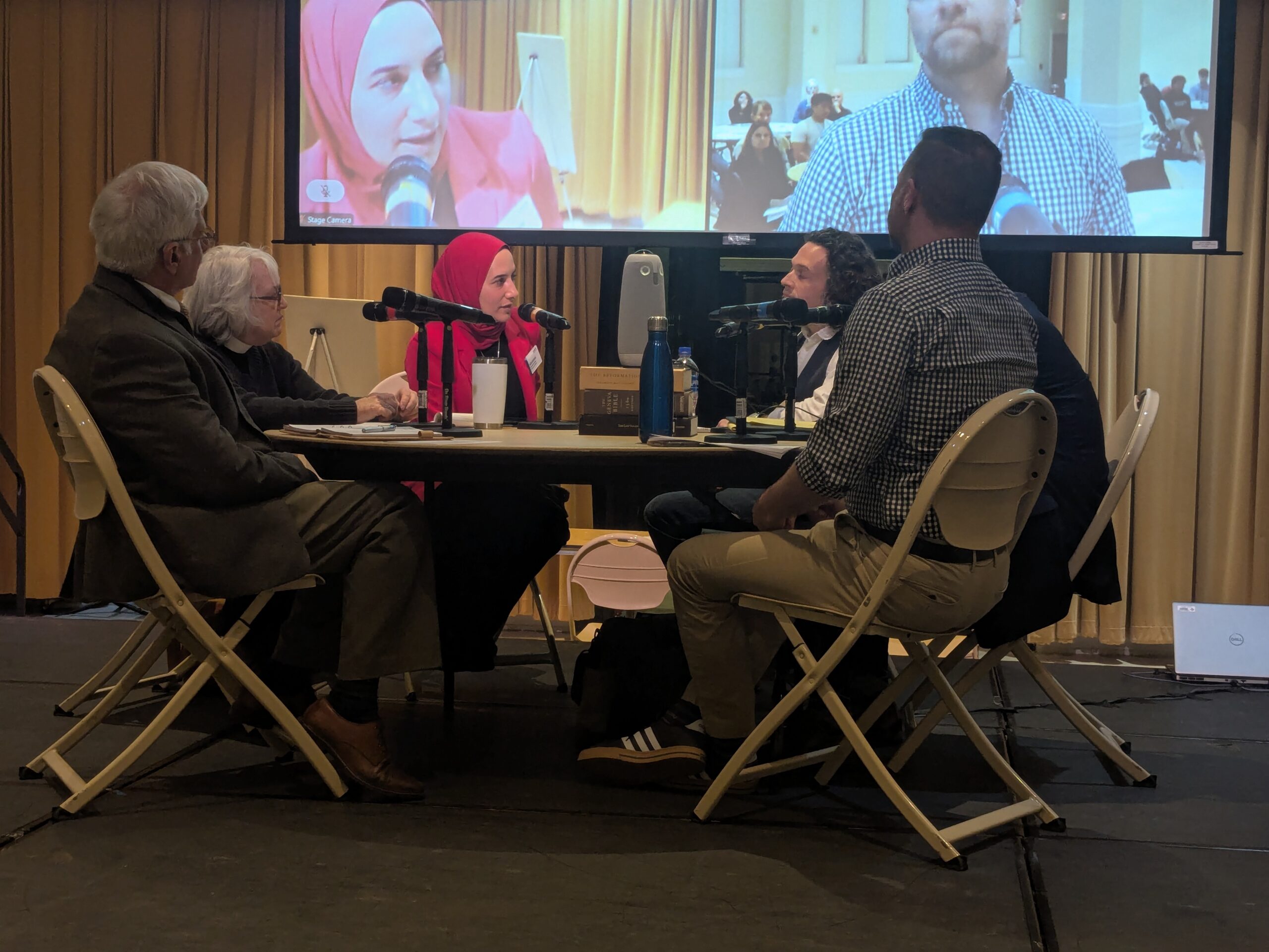 photo of panelists sitting around a table with a screen in the background.
