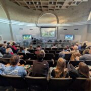 Photo of audience watching screens at Watch Party