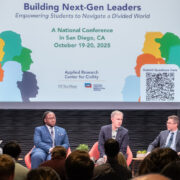 Panelists sitting in front of a screen on a stage